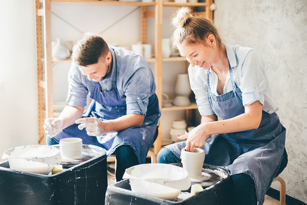 Two craftsmen create pottery for an event together.